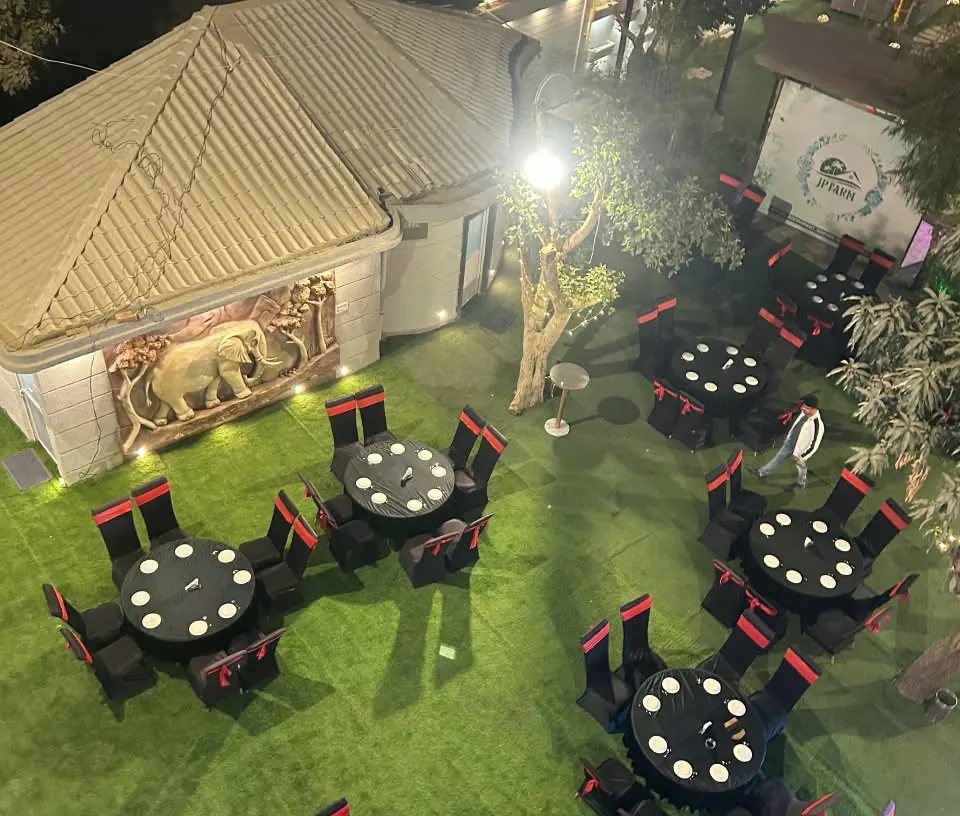 Garden lawn at Hotel J P Farm set with round tables for an evening event