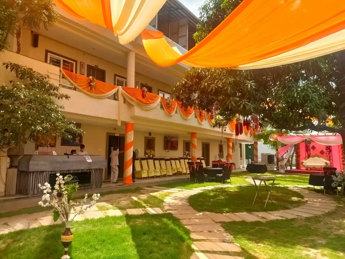 Courtyard at Hotel J P Farm decorated in orange and cream drapes with a stage set for a haldi ceremony